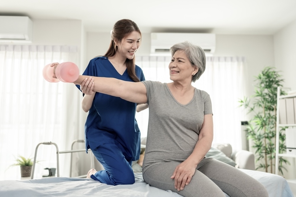 Staff assisting female elderly patient in stretching in skilled nursing facility